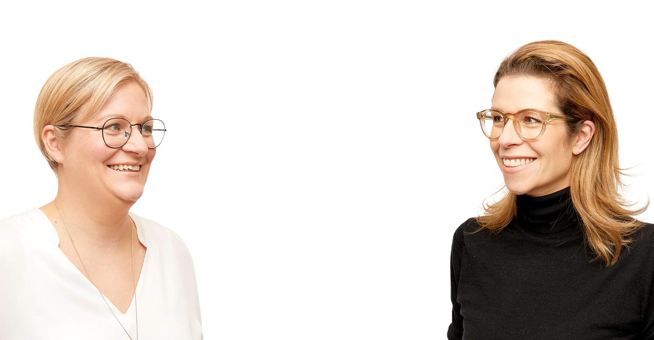 Frau Frank und Mandantin mit Brille schauen sich an und lachen